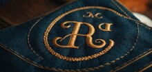  A Close Up Of A Blue Cloth With A Gold Monogrammed Letter And A Monogrammed Monogram On The Front Of The Back Of The Pocket Of The Pocket.