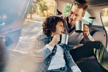 Happy Father And Son Drinking Warm Drinks In Car Trip