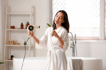 Canvas Print - Pretty young Asian woman drying hair and singing in bathroom