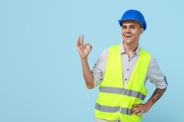 Young male engineer showing OK on blue background