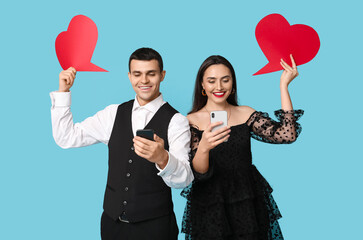 Wall Mural - Young couple with mobile phones and speech bubbles on blue background. Online dating