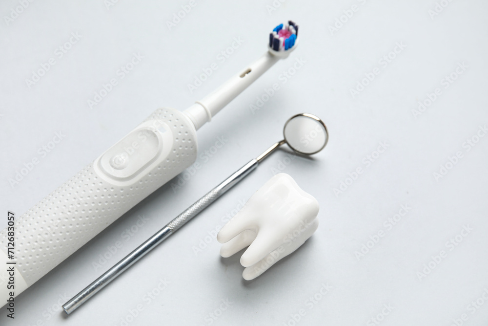 Dental mirror, tooth model and electric toothbrush on white background ...