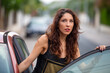 © carloskoblischek - Mujer joven abriendo la puerta de su coche mirando con asombro lo que está pasando en la calle