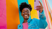 Happy Young Black Woman In Stylish Casual Clothes And Taking Selfie With Smartphone Against Bold Color Building Wall With Graffiti Background