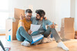 Worried gay couple having financial problems looking at paper documents arguing in new apartment.