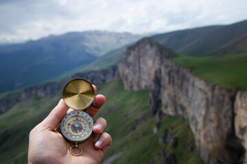 Wall Mural - compass in hand of man on mountain top. compass on top of mountain.