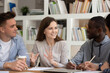 © fizkes - Motivated international young people sit at table studying together sharing discussing ideas, smiling smart multiracial millennial students cooperate brainstorm working on school project in classroom