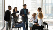 © fizkes - Business coaching. Young black male experienced mentor speak to mixed race group of students interns at seminar workshop. Interested millennial staff engaged in practical training on sales management