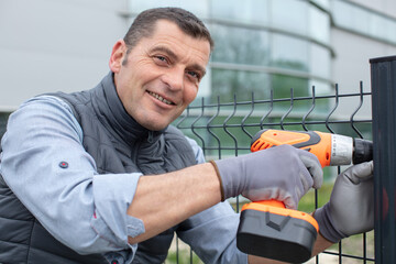 Wall Mural - worker installing welded metal mesh fence