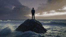 A Man Standing On A Rock In The Ocean