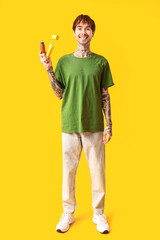 Poster - Happy young man with paint and roller on yellow background