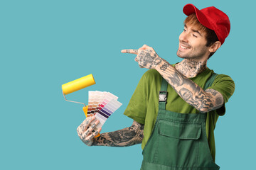 Poster - Male painter with palette samples and paint roller pointing at something on color background