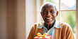 © Alena Yakusheva - natural portrait of a senior elderly black skinned man with a gift box, blurred home interior background