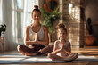Parent and her charming little daughter are smiling while doing yoga together at home