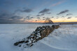 An old stone fence and a fish drying rack on a beautiful but cold winter day during the polar night
