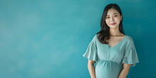 Banner with a pregnant confident modern happy young Asian woman on studio blue background and copy space