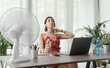© StockPhotoPro - Woman cooling herself with an electric fan