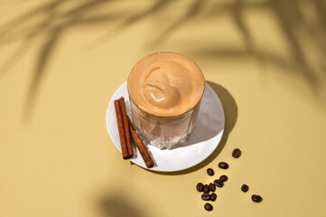 Wall Mural - Dalgona coffee. Whipped instant coffee in a glass on a saucer with cinnamon sticks