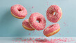 Flying pink sprinkled donuts. Sweet doughnut on pastel blue background.