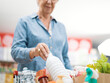 © StockPhotoPro - Senior woman putting goods in the shopping cart