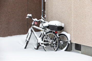 Bicycles at the wall of the house after a snowfall, winter time