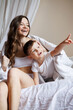 © Dmytro Hai - Smiling toddler boy in pajama pointing away near mom on bed in morning
