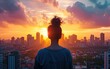 A woman stands with her back to the viewer, gazing at a vibrant sunset beyond the silhouette of a city skyline.