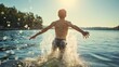 Rearview photography of a young boy running or walking in sea, river or lake water on a sunny summer day. Youthful shirtless child wearing shorts, splashing the water into air, having fun