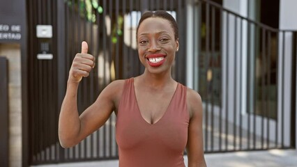 Wall Mural - Joyful african american woman in city streets giving an excellent sign, standing tall with radiant smile showing approval. successfully spreading positivity and happiness