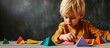 Little blond boy with help of adult in kindergarten put figures made of geometric shapes on the table. Copy space image. Place for adding text