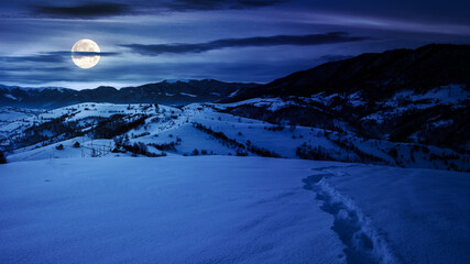 Wall Mural - mountainous winter landscape at night. scenery with snow covered hills in the distance beneath cloud