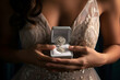 Beautiful young woman in wedding dress with diamond ring in hand.
