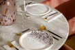 Dining table arrangement with ceramic black and white plates, gold flatware set with black handles and wine glasses,