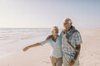 © Marko Geber - Happy senior couple walking on sunny beach
