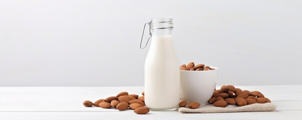 a glass of white milk with almond kernels nearby white background copy space
