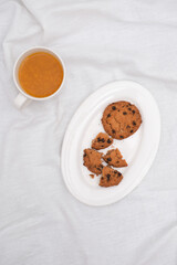 Vitaminic healthy sea buckthorn tea with biscuits on white plate on white background, selective focus, copy space