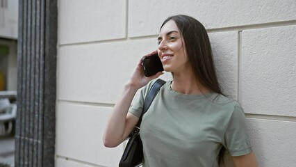 Wall Mural - Young beautiful hispanic woman smiling confident talking on the smartphone at street