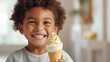 Young child with a big smile holding a vanilla ice cream cone in a bright indoor setting