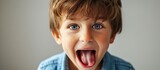 Fototapeta  - A six year old boy child is being funny and making a bratty face while sticking out his tongue. Copy space image. Place for adding text or design