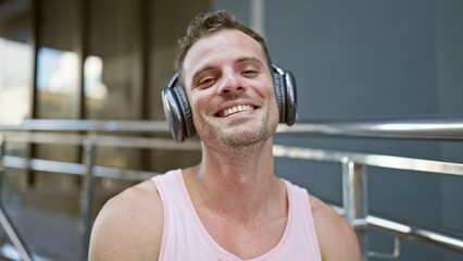 Sticker - Smiling man with headphones enjoying music outdoors in an urban setting, exuding casual style and positivity.