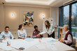 © qunica.com - A professional and diverse group of colleagues engaging in a business meeting in a well-lit office. The image depicts teamwork, discussion, and the sharing of ideas among employees.