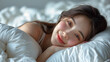 Smiling young asian woman lying in the bed before sleeping.
