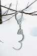 Handcuffs hang on a branch in winter on a background of snow with human traces, a concept on the theme of escape