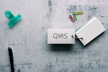 Wall Mural - There is word card with the word QMS. It is an abbreviation for Quality Management System as eye-catching image.