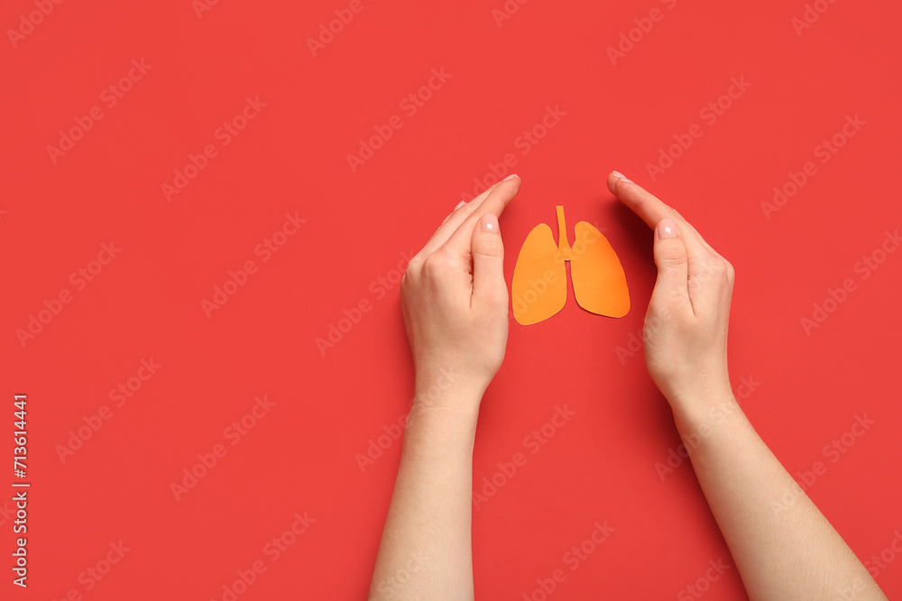 Female hands with paper lungs on red background. Lung cancer concept