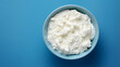 Cottage cheese in a bowl on a blue background, top view	
