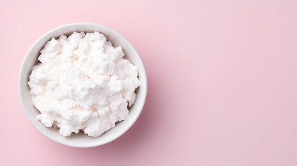 Cottage cheese in white bowl on pink background with copy space.