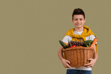 Sticker - Cute little boy holding wicker basket with different vegetables on green background