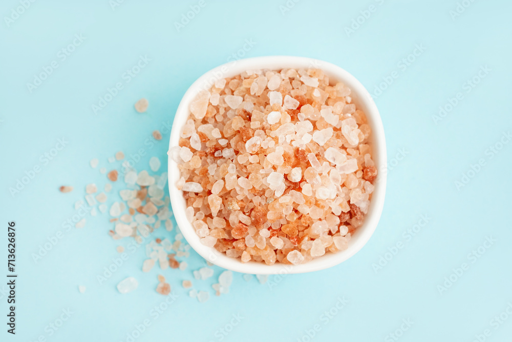 Bowl with Himalayan pink salt on blue background