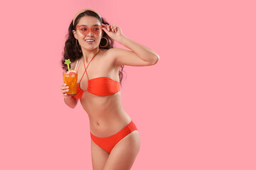 Poster - Sexy young woman in swimsuit drinking cocktail on pink background